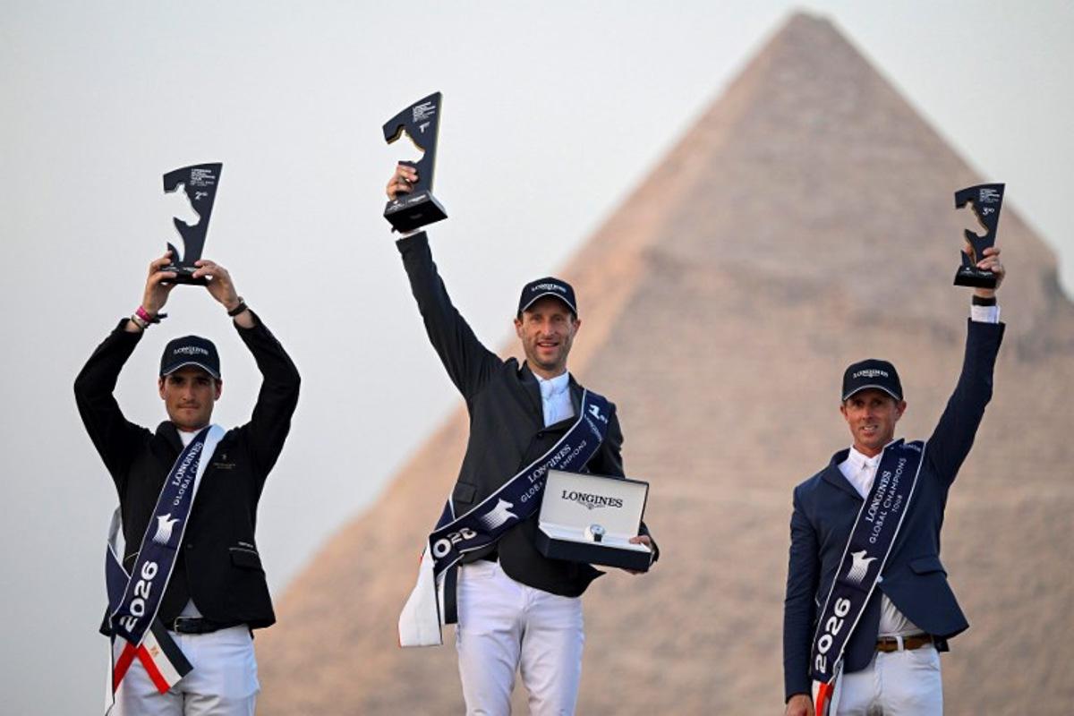 Belgium's first-place winner Pieter Devos (C), second-place winner Olivier Philippaerts (L), and England's third-place winner Ben Maher celebrate on the podium after the Longines Global Champions Tour 2026 at the Giza pyramids, west of Cairo on October 24, 2026.  Khaled DESOUKI / AFP