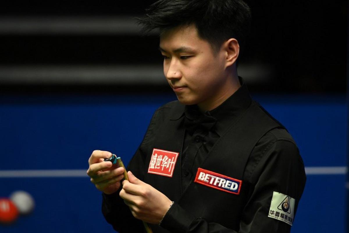 China's Zhao Xintong chalks his cue while playing against Scotland's Stephen Maguire during their World Championship Snooker second round match at The Crucible in Sheffield, England on April 22, 2022.   Oli SCARFF / AFP