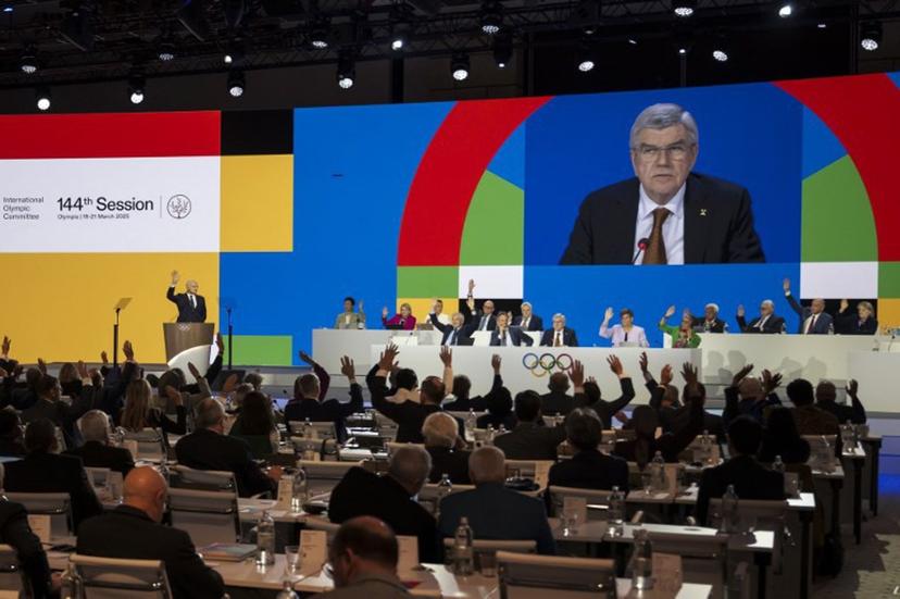 Outgoing International Olympic Committee (IOC) President Thomas Bach is seen on a giant screen while IOC members vote on boxing during the 144th IOC Session, in Costa Navarino, Greece, on the election day of the next IOC President, on March 20, 2025. Boxing will be part of the program of 2028 Summer Games in Los Angeles 2028 Olympics after IOC members unanimously approved a resolution by the IOC executive board. Fabrice COFFRINI / AFP