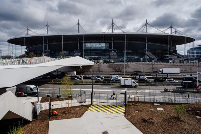 This photograph taken on March 28, 2024 shows a view of the footbridge connecting the 'Stade de France' stadium with the Aquatics Centre built for the Paris 2024 Olympic Games to be used for artistic swimming, diving and water polo competitions in Saint Denis, near Paris. VenhoevenCS & Ateliers 2/3/4/ designed the building. The Seine-Saint-Denis department north of Paris will host a number of events for the Paris 2024 Olympic and Paralympic Games, with venues including the Stade de France and Aquatics Centre, as well as the Olympic Village.  Dimitar DILKOFF / AFP