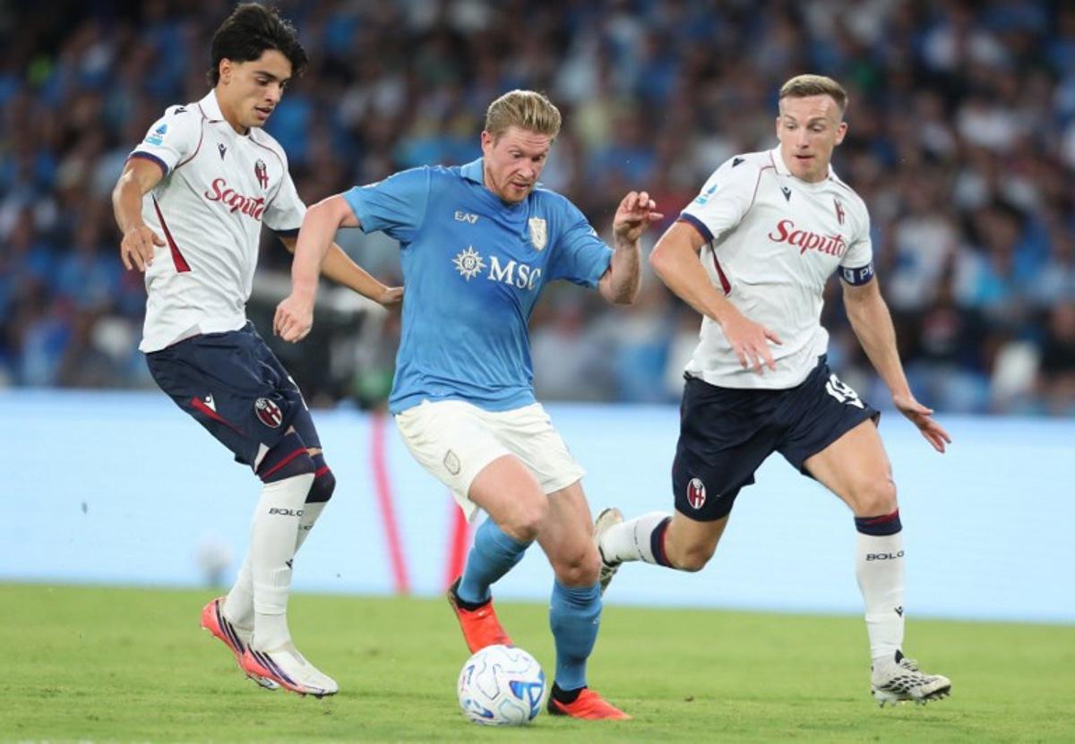 Napoli's Belgian midfielder #11 Kevin De Bruyne (C) fights for the ball with Bologna's Venezuelan midfielder #18 Marco Libra (L) and Bologna's Scottish midfielder #19 Lewis Ferguson (R)   during the Italian Serie A football match SSC Napoli vs Bologna FC 1909 at the Diego Armando Maradona Stadium in Naples on September 13, 2026.  CARLO HERMANN / AFP