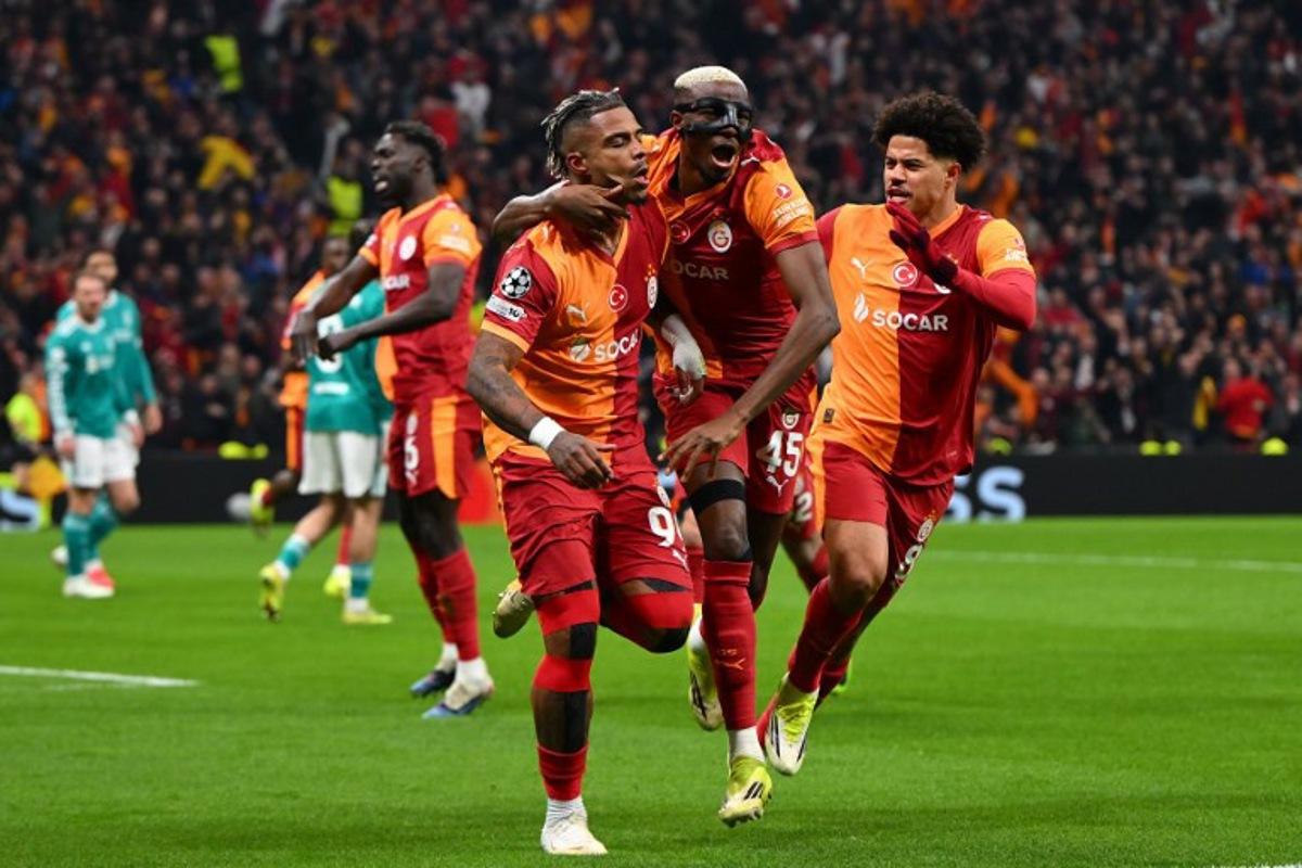 Galatasaray's Gabonese midfielder #99 Mario Lemina (L) celebrates with teammates after scoring the opening goal during the UEFA Champions League round of 16 first leg football match between Galatasaray SK and Liverpool FC at the Ali Sami Yen Sports Complex in Istanbul on March 10, 2026.  YASIN AKGUL / AFP