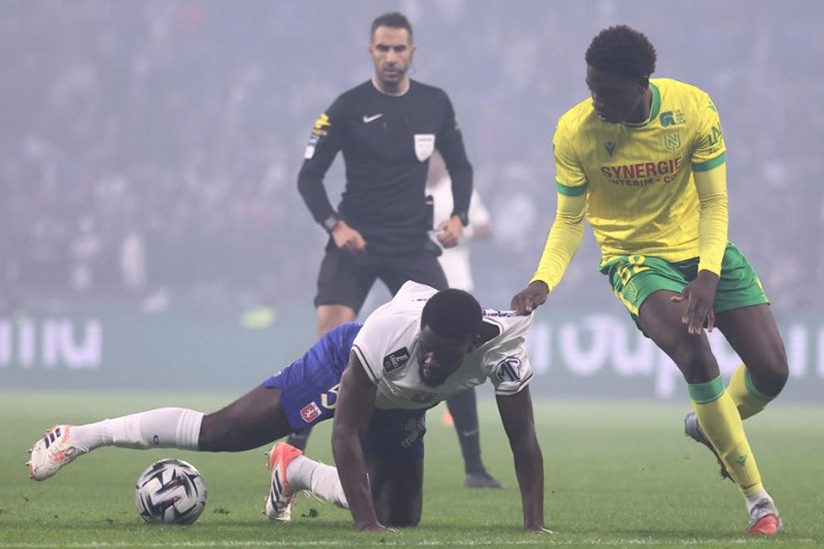 Lyon's Belgian midfielder #05 Orel Mangala (down) fights for the ball with Nantes' French midfielder #52 Bahmed Deuff (R) during the French L1 football match between Olympique Lyonnais (OL) and FC Nantes at the Parc Olympique Lyonnais stadium in Decines-Charpieu, central-eastern France on November 30, 2025.  Alex MARTIN / AFP