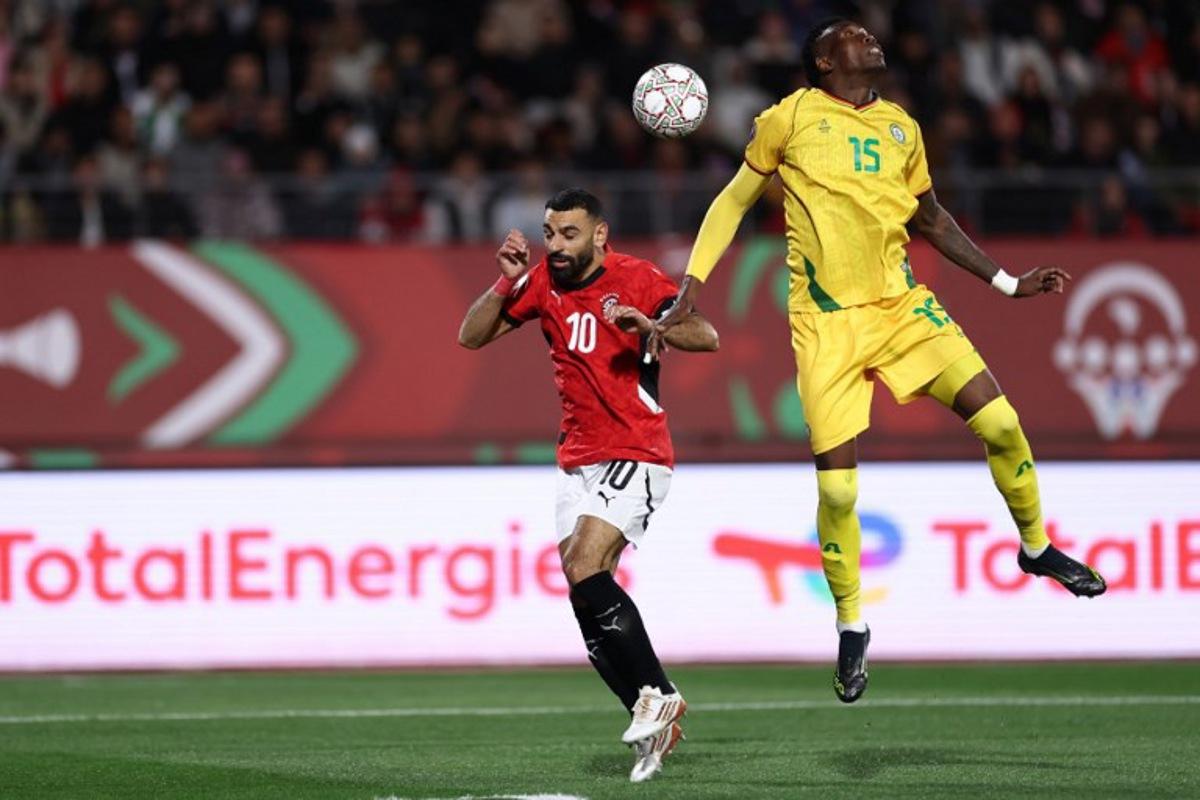 Egypt's forward #10 Mohamed Salah and Zimbabwe's defender #15 Teenage Hadebe jump for the ball during the Africa Cup of Nations (CAN) group B football match between Egypt and Zimbabwe at Adrar Stadium in Agadir on December 22, 2025.   FRANCK FIFE / AFP