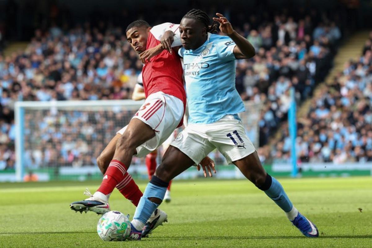 Arsenal's Spanish defender #03 Christhian Mosquera (L) is challenged by Manchester City's Belgian midfielder #11 Jeremy Doku (R) during the English Premier League football match between Manchester City and Arsenal at the Etihad Stadium in Manchester, north west England, on April 19, 2026.  Darren Staples / AFP