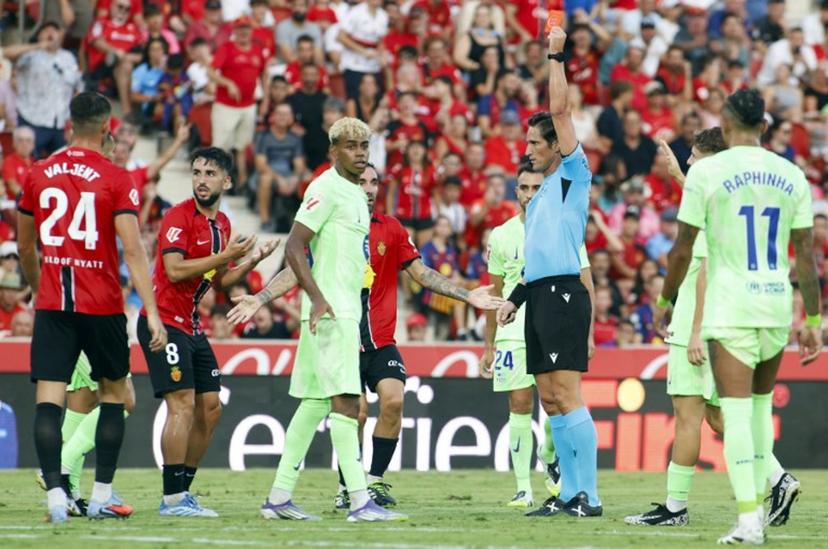 Spanish referee Jose Luis Munuera Montero presents a red card to Real Mallorca's Spanish midfielder #8 Manu Morlanes (2L) during the Spanish league football match between RCD Mallorca and FC Barcelona at Mallorca Son Moix Stadium in Palma de Mallorca on August 16, 2025.  JAIME REINA / AFP