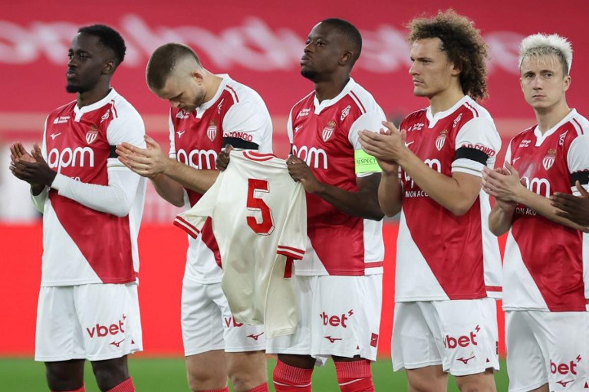 Monaco's Swiss midfielder #06 Denis Zakaria (C) holds a jersey of late Monaco player Rolland Coubis during a tribute before the French L1 football match between AS Monaco and FC Lorient at the Louis II Stadium (Stade Louis II) in the Principality of Monaco on January 16, 2026.  Valery HACHE / AFP