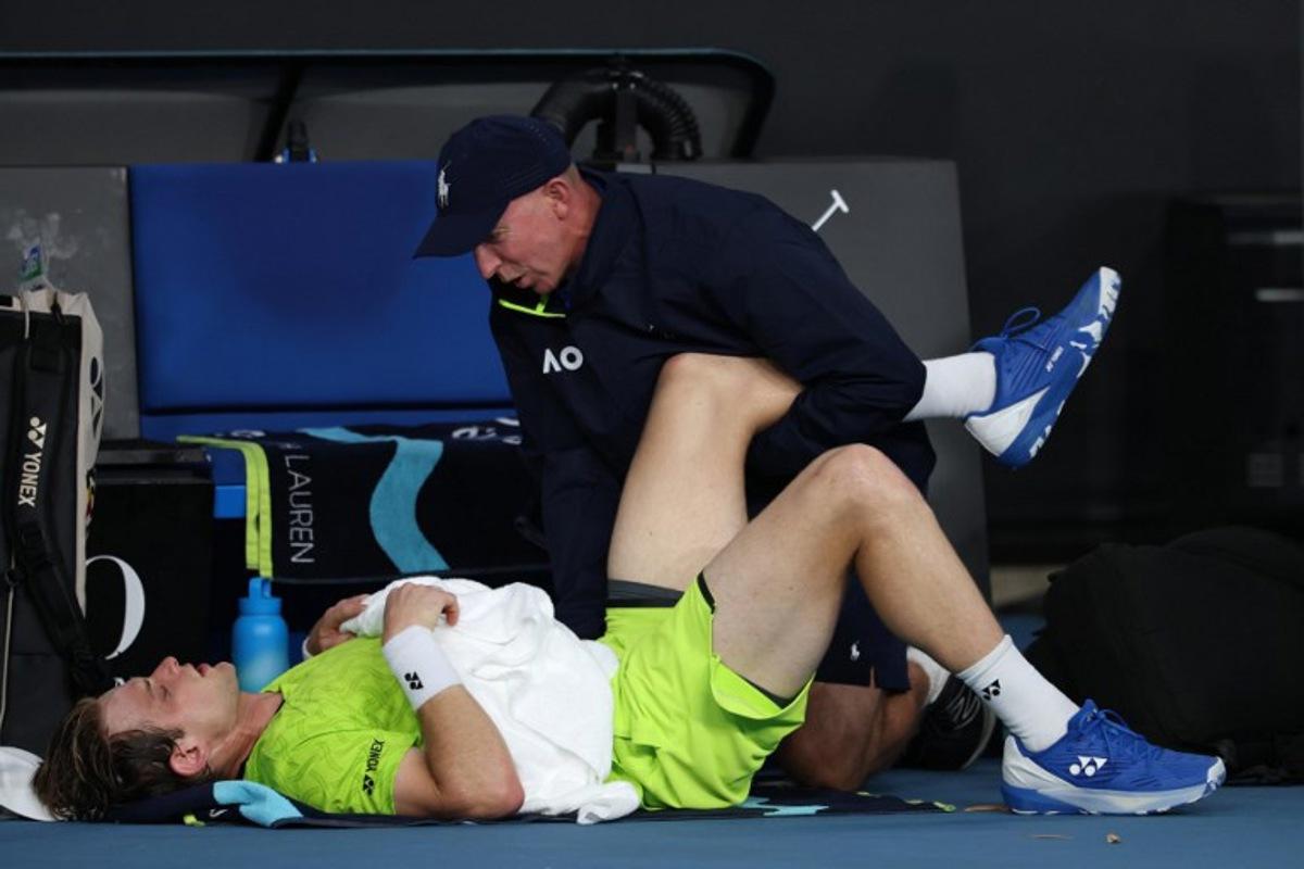 A physio attends to Belgium's Zizou Bergs between points against Poland's Hubert Hurkacz during their men's singles match on day three of the Australian Open tennis tournament in Melbourne on January 20, 2026.  IZHAR KHAN / AFP