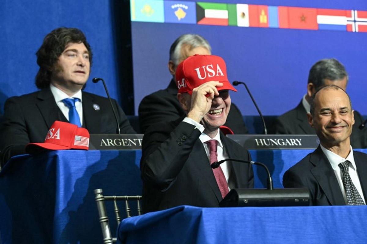 FIFA President Gianni Infantino puts on a "USA" hat as he attends the inaugural meeting of the "Board of Peace" hosted by US President Donald Trump at the US Institute of Peace in Washington, DC, on February 19, 2026. President Trump on Thursday gathers allies to inaugurate the "Board of Peace," his new institution focused on progress on Gaza but whose ambitions reach much further. Around two dozen world leaders or other senior officials have come to Washington for the meeting -- including several of Trump's authoritarian-leaning friends and virtually none of the European democrats that traditionally sign on to US initiatives.  SAUL LOEB / AFP