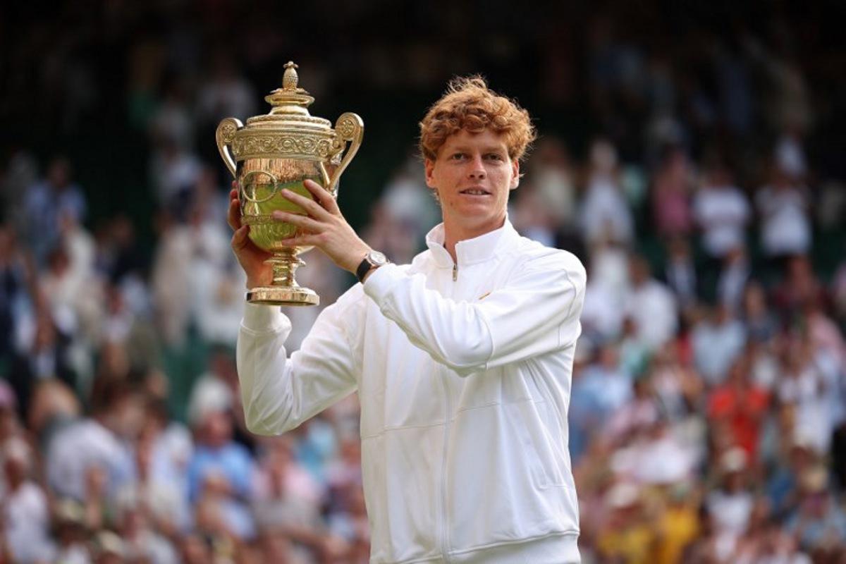 Italy's Jannik Sinner celebrates with the winner's trophy as he poses for pictures following his victory against Spain's Carlos Alcaraz at the end of their men's singles final tennis match on the fourteenth day of the 2025 Wimbledon Championships at The All England Lawn Tennis and Croquet Club in Wimbledon, southwest London, on July 13, 2025.  HENRY NICHOLLS / AFP