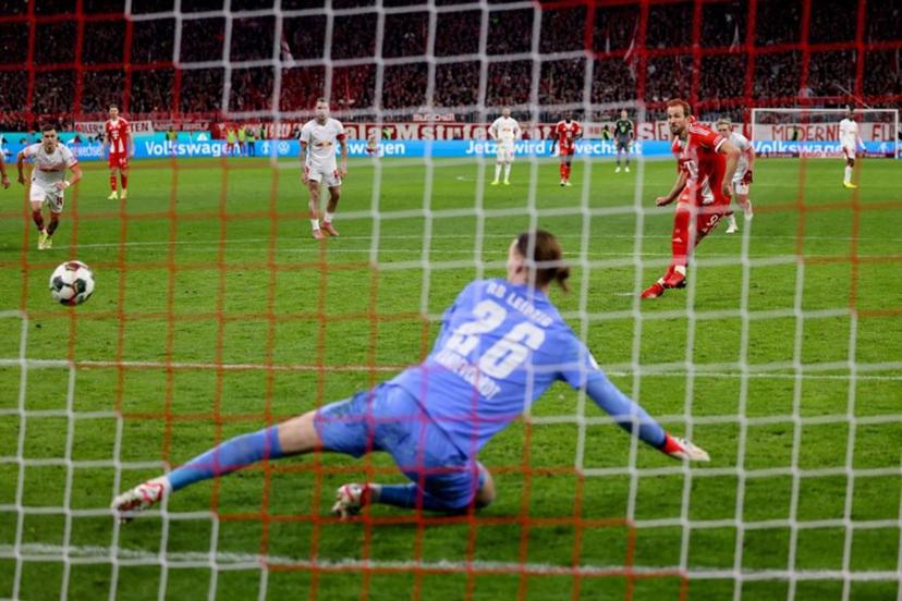 Bayern Munich's English forward #09 Harry Kane (R) scores the opening goal from the penalty spot past Leipzig's Belgian goalkeeper #26 Maarten Vandevoordt during the German Cup (DFB-Pokal) quarter-final football match between FC Bayern Munich and RB Leipzig in Munich, southern Germany on February 11, 2026.  Alexandra BEIER / AFP