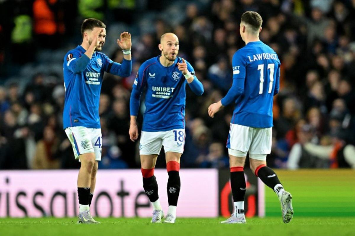 Rangers' Welsh striker #11 Tom Lawrence is congratulated by teammates Rangers' Scottish goalkeeper #41 Lewis Budinauckas (L) and Rangers' Czech midfielder #18 Vaclav Cerny after scoring a penalty during the UEFA Europa League second-leg round of 16 football match between Rangers and Fenerbahce SK at the Ibrox Stadium in Glasgow on March 13, 2025.  ANDY BUCHANAN / AFP