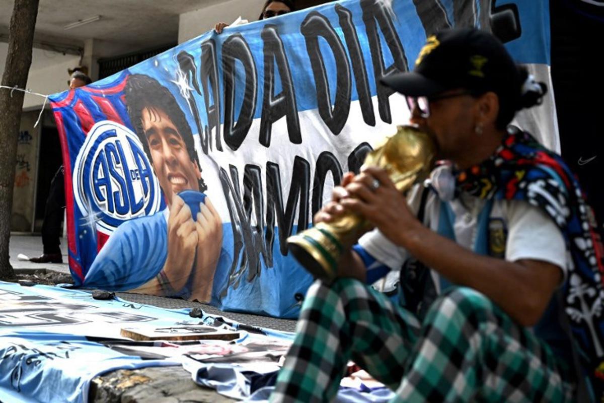 A banner depicting late Diego Maradona is seen as a fan waits outside the San Isidro court during the trial for the death of Argentine football legend in San Isidro, Buenos Aires province, Argentina on March 11, 2025. Four years after Diego Maradona's death, the trial of seven health professionals begins this Tuesday in Argentina to determine their responsibilities in the death of the soccer legend. Luis ROBAYO / AFP
