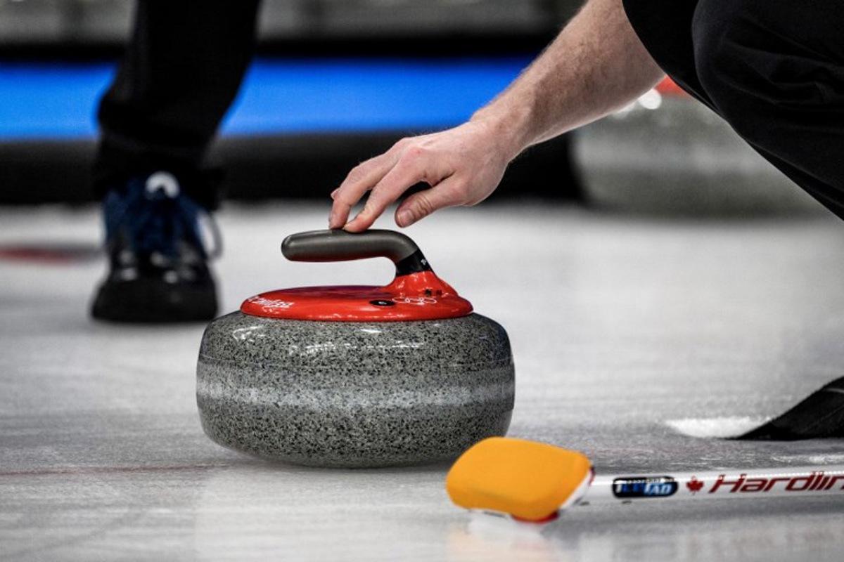 A competitor prepares to curl the stone during the men's bronze medal game of the Beijing 2022 Winter Olympic Games curling competition between Canada and USA at the National Aquatics Centre in Beijing on February 18, 2022.  Jeff PACHOUD / AFP