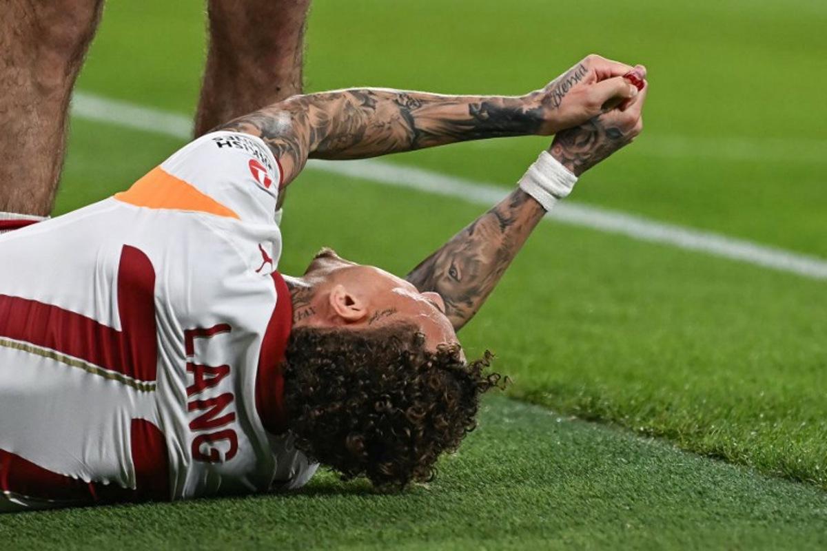 Galatasaray's Dutch forward #77 Noa Lang reacts on the floor after cutting his thumb during the UEFA Champions League, round of 16 second leg football match between Liverpool and Galatasaray at Anfield in Liverpool, north-west England on March 18, 2026.  Paul ELLIS / AFP