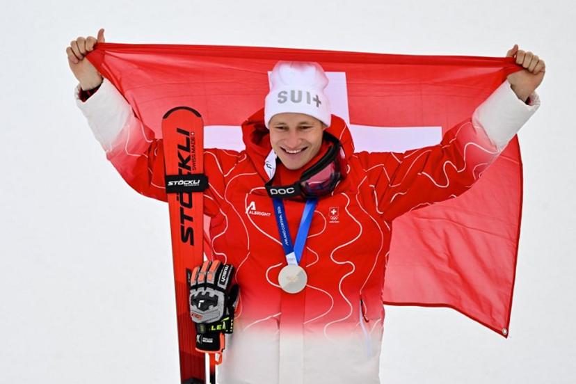 Switzerland's silver medalist Marco Odermatt holds up a Swiss flag after the men's giant slalom alpine skiing event during the Milano Cortina 2026 Winter Olympic Games at the Stelvio Ski Centre in Bormio (Valtellina) on February 14, 2026.  Fabrice COFFRINI / AFP