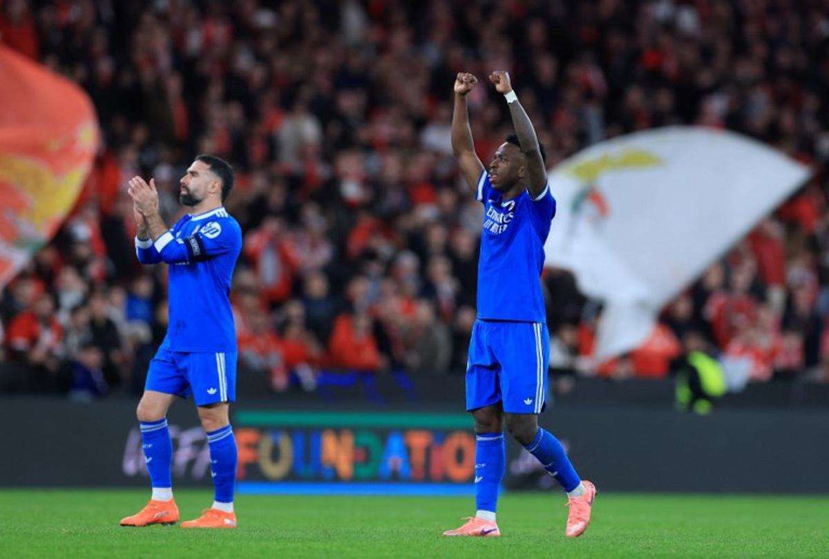 Real Madrid's Brazilian forward #07 Vinicius Junior celebrates with Real Madrid's Spanish defender #02 Dani Carvajal at the end of the UEFA Champions League knockout round play-off first leg football match between SL Benfica and Real Madrid CF at Estadio da Luz in Lisbon on February 17, 2026. Real Madrid won 0-1. PATRICIA DE MELO MOREIRA / AFP