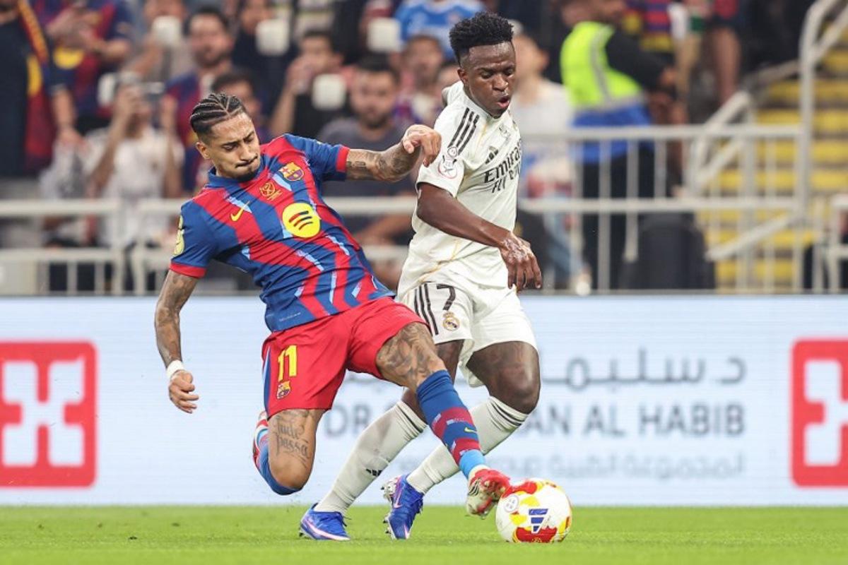 Barcelona's Brazilian forward #11 Raphinha (L) and Real Madrid's Brazilian forward #07 Vinicius Junior fight for the ball during the Spanish Super Cup final football match between FC Barcelona and Real Madrid at the King Abdullah Stadium in Jeddah on January 11, 2026.  Haitham AL-SHUKAIRI / AFP