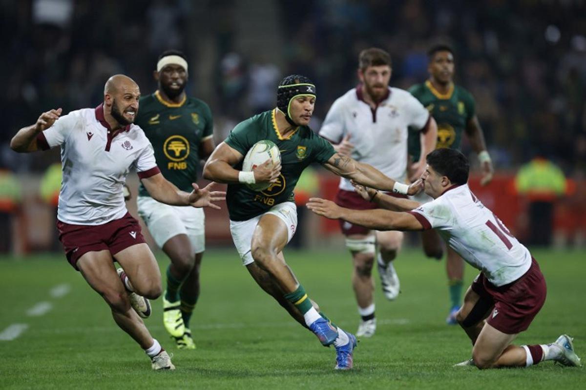 South Africa's wing Edwill van der Merwe runs away from Georgia's centre Demuri Tapladze (L) and Georgia's fly-half Luka Matkava (R) during the international rugby union Test match between South Africa and Georgia at Mbombela Stadium in Mbombela on July 19, 2025.  PHILL MAGAKOE / AFP
