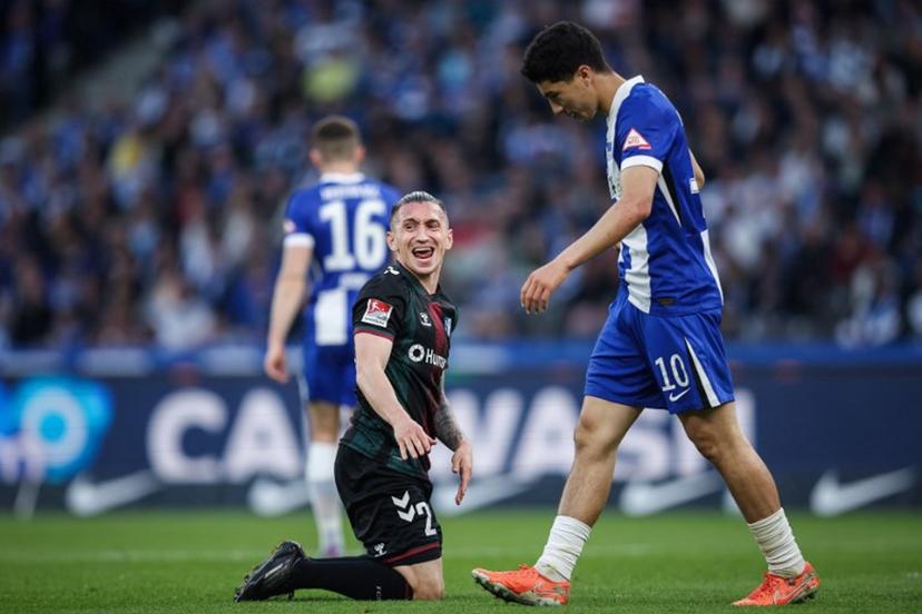 Magdeburg's Turkish forward #23 Baris Atik (L) reacts next to Berlin's Algerian forward #10 Ibrahim Maza (R) during the Bundesliga second division football match between Hertha BSC vs 1 FC Magdeburg at the Olympic Stadium (Olympiastadion) in Berlin, Germany on April 25, 2025. Driven by huge crowds, unpredictable results and some of Germany's biggest clubs, the Bundesliga 2 broke through the billion euro barrier last season to become Europe's wealthiest second flight. Ronny Hartmann / AFP