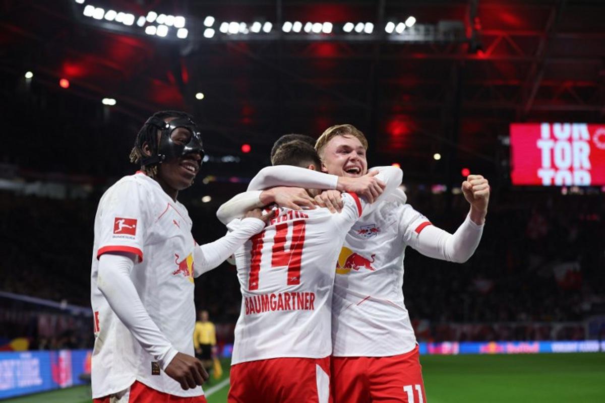 Leipzig's Danish forward #11 Conrad Harder (R) celebrates scoring the 1-0 opening goal with Leipzig's Ivorian forward #49 Yan Diomande (L) and Leipzig's Austrian midfielder #14 Christoph Baumgartner (C) during the German first division Bundesliga football match between RB Leipzig and Eintracht Frankfurt in Leipzig, eastern Germany, on December 6, 2025.  Ronny HARTMANN / AFP