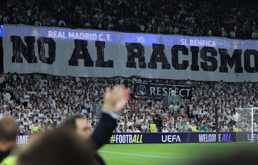 A banner against racism is pictured before the UEFA Champions League knockout round play-off second leg football match between Real Madrid CF and SL Benfica at Santiago Bernabeu Stadium in Madrid on February 25, 2026.  Thomas COEX / AFP