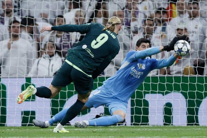 Real Madrid's Belgian goalkeeper #01 Thibaut Courtois (R) makes a save from a shot on goal by Manchester City's Norwegian forward #09 Erling Braut Haland during the UEFA Champions League league phase day 6 football match between Real Madrid CF and Manchester City at Santiago Bernabeu Stadium in Madrid on December 10, 2025.  Oscar DEL POZO / AFP