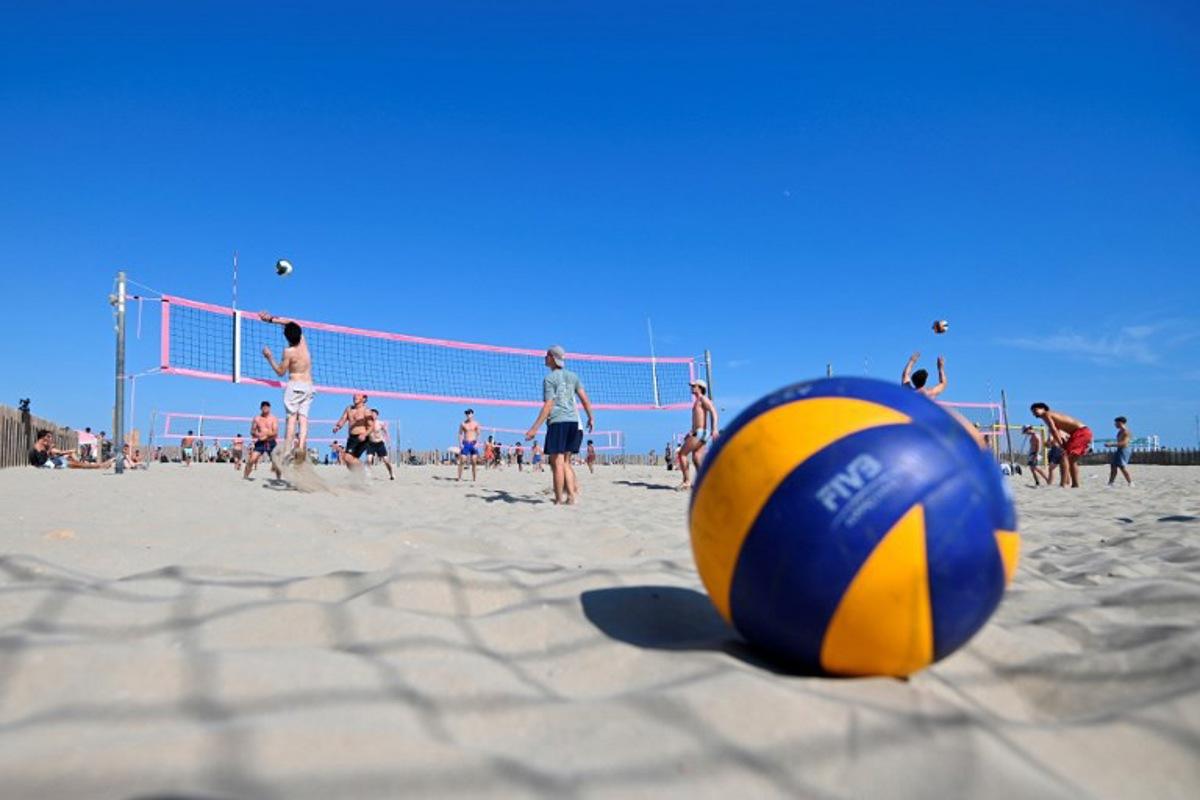 Beach-goers play beach volleyball on the beach in Carnon, southern France, on July 14, 2024.  From Montpellier to Narbonne via Sète, from gymnasiums to beaches via the villages of the hinterland, French volleyball has shined for almost 100 years with a particular brilliance on the banks of the Mediterranean, far from Paris which hosts the Olympic Games. Sylvain THOMAS / AFP