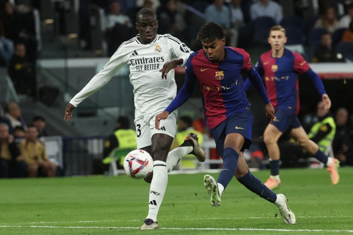 Barcelona's Spanish forward #19 Lamine Yamal (R) is challenged by Real Madrid's French defender #23 Ferland Mendy during the Spanish league football match between Real Madrid CF and FC Barcelona at the Santiago Bernabeu stadium in Madrid on October 26, 2024.  Pierre-Philippe MARCOU / AFP