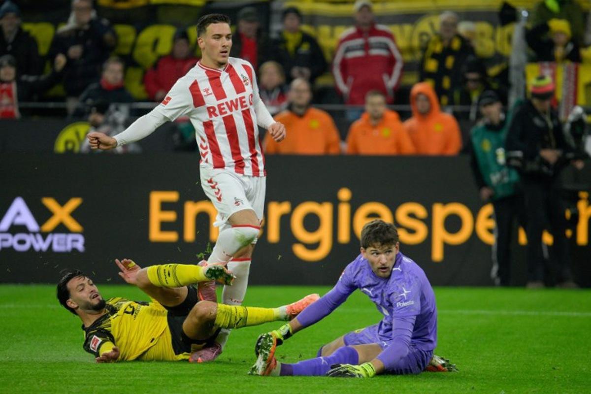 FC Cologne's German midfielder #13 Said El Mala (C) is tackled by Dortmund's Algerian defender #05 Ramy Bensebaini (L) in front of Dortmund's Swiss goalkeeper #01 Gregor Kobel's goal during the German first division Bundesliga football match between BVB Borussia Dortmund and 1 FC Cologne in Dortmund, Germany on October 25, 2025.  Sascha Schuermann / AFP