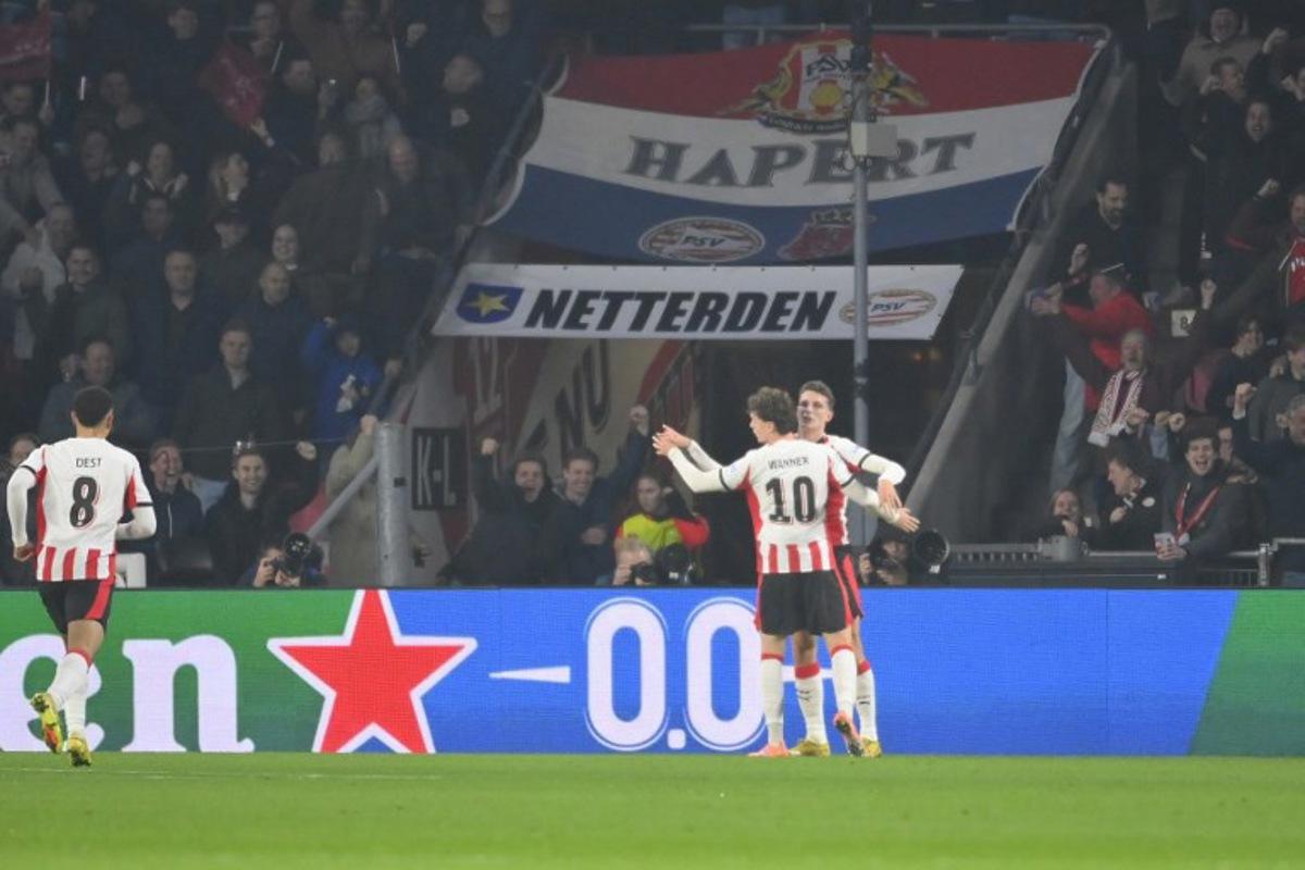 PSV Eindhoven's Dutch midfielder #20 Guus Til (R) celebrates scoring his team's first goal with teammates during the UEFA Champions League, league phase day 6, football match between PSV Eindhoven (NED) and Atletico Madrid (ESP), at the Philips Stadion, in Eindhoven, south of The Netherlands, on December 9, 2025.  JOHN THYS / AFP