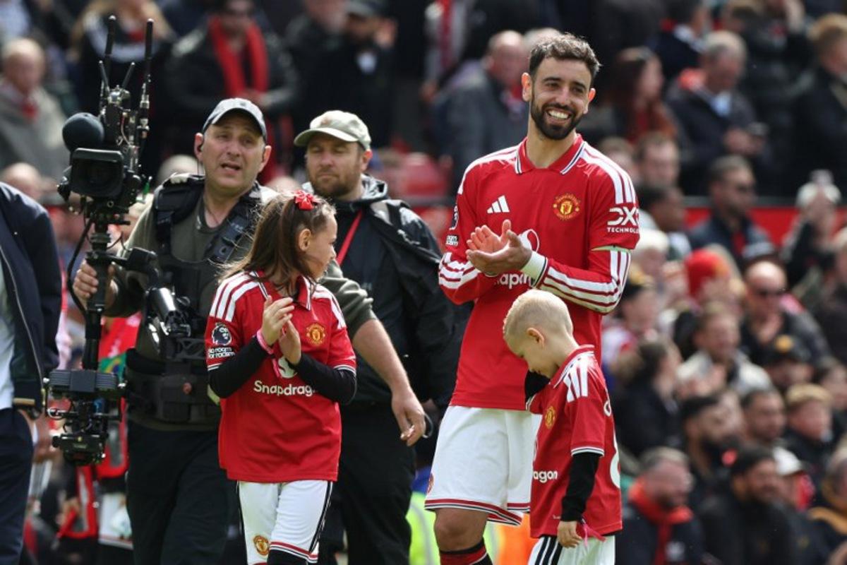 Manchester United's Portuguese midfielder #08 Bruno Fernandes (R) smiles on the pitch after their final home appearance in the English Premier League football match between Manchester United and Nottingham Forest at Old Trafford in Manchester, north west England, on May 17, 2026. United won the game 3-2. Darren Staples / AFP