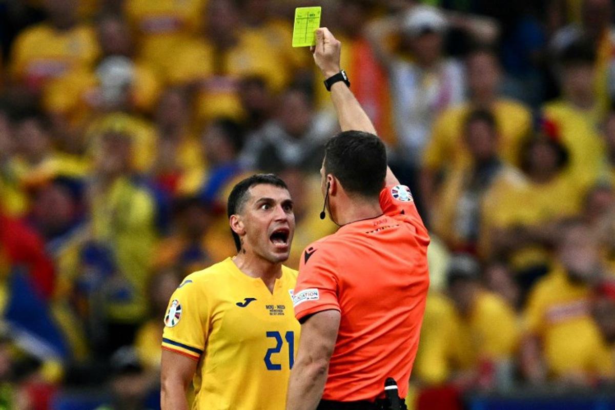 German referee Felix Zwayer shows a yellow card to Romania's midfielder #21 Nicolae Stanciu during the UEFA Euro 2024 round of 16 football match between Romania and the Netherlands at the Munich Football Arena in Munich on July 2, 2024.  Fabrice COFFRINI / AFP