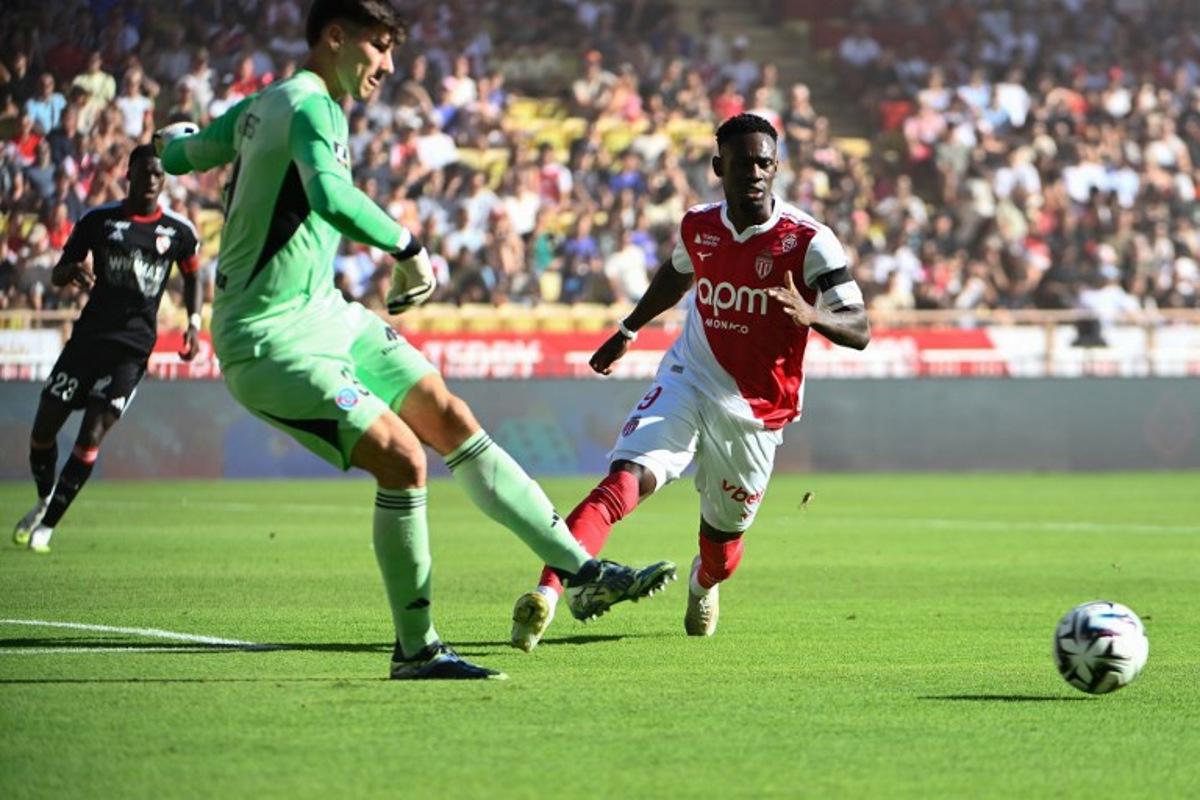 Strasbourg's Belgian goalkeeper #39 Mike Penders (L) shoots the ball next to Monaco's American forward #09 Folarin Balogun (R) during the French L1 football match between AS Monaco and RC Strasbourg Alsace at the Louis II Stadium in the Principality of Monaco on August 31, 2025.  FREDERIC DIDES / AFP