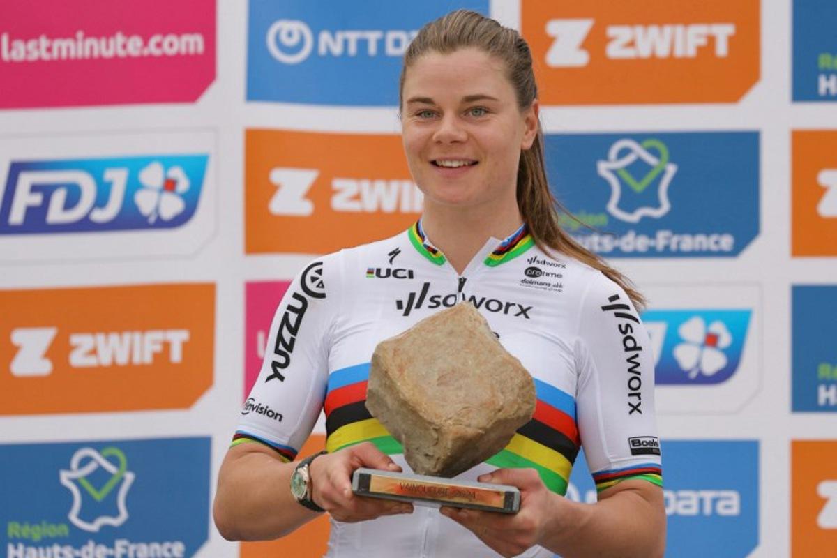 Team SD Worx - Protime's Belgian rider Lotte Kopecky celebrates on the podium with the cobblestone trophy after winning the fourth edition of the women's Paris-Roubaix one-day classic cycling race, 148,5km between Denain and Roubaix, on April 6, 2024.  Thomas SAMSON / AFP