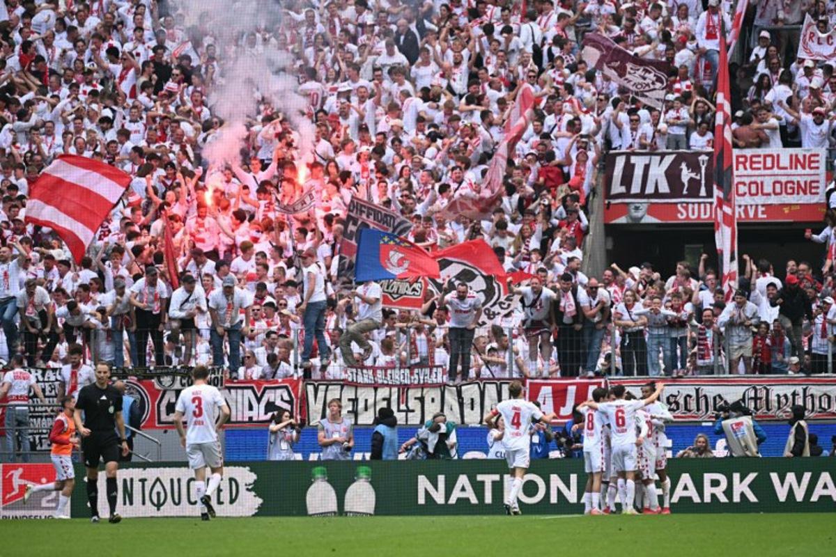 FC Cologne's German forward #09 Luca Waldschmidt (Hidden) celebrates with his team mates after scoring his team's second goal during the German second division Bundesliga football match between FC Cologne and FC Kaiserslautern in Cologne, western Germany on May 18, 2025.  INA FASSBENDER / AFP