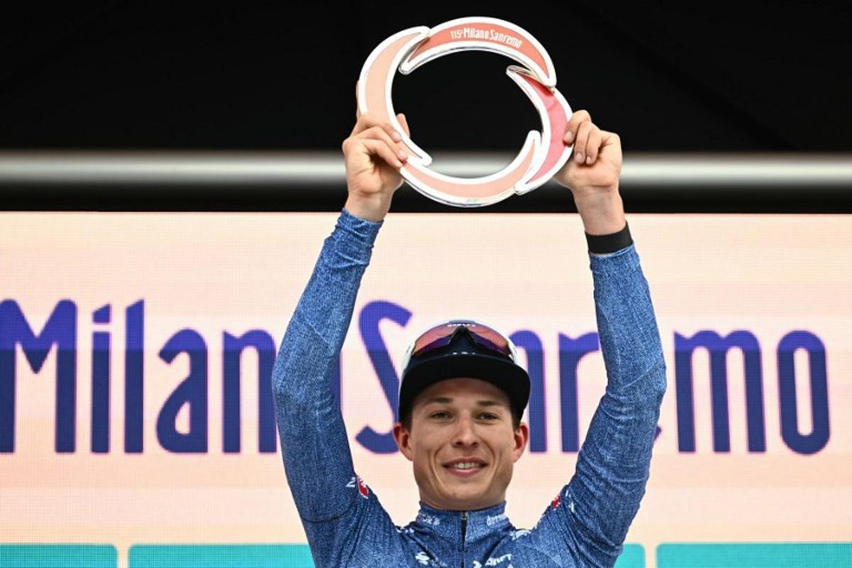 Alpecin-Deceuninck's Belgian rider Jasper Philipsen celebrates with the trophy on the podium after winning the 115th Milan-SanRemo one-day classic cycling race, between Pavia and SanRemo, on March 16, 2024.  Marco BERTORELLO / AFP