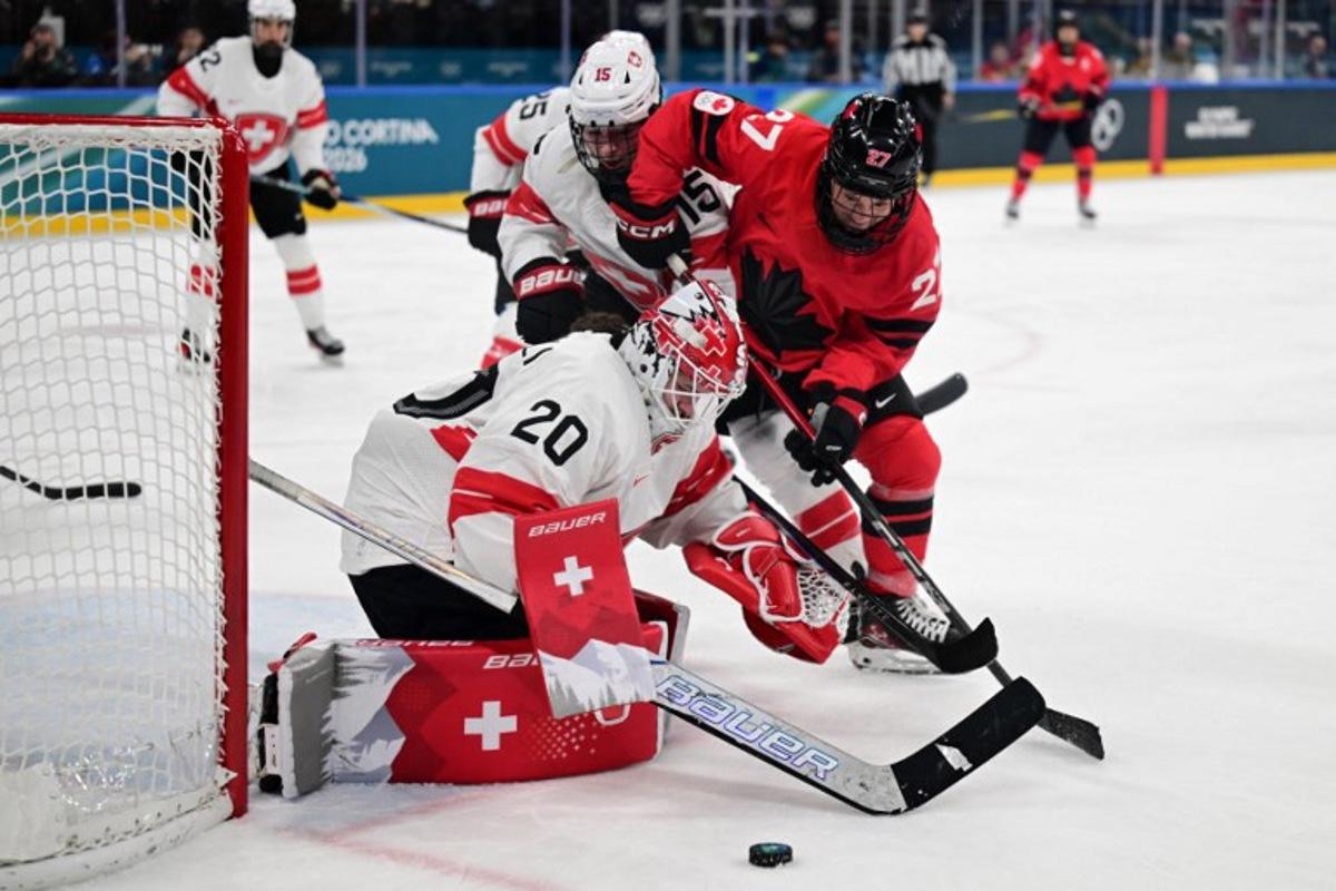 Switzerland's goalkeeper #20 Andrea Braendli (L) makes a save during the women's play-off semi-final ice hockey match between Canada and Switzerland at the Milano Santagiulia Ice Hockey Arena during the Milano Cortina 2026 Winter Olympic Games in Milan, on February 16, 2026.  Piero CRUCIATTI / AFP