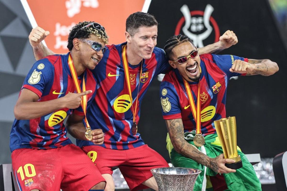 Barcelona's Spanish forward #10 Lamine Yamal, Polish forward #09 Robert Lewandowski and Brazilian forward #11 Raphinha celebrate after winning the Spanish Super Cup final football match between FC Barcelona and Real Madrid at the King Abdullah Stadium in Jeddah on January 11, 2026.  Fadel SENNA / AFP
