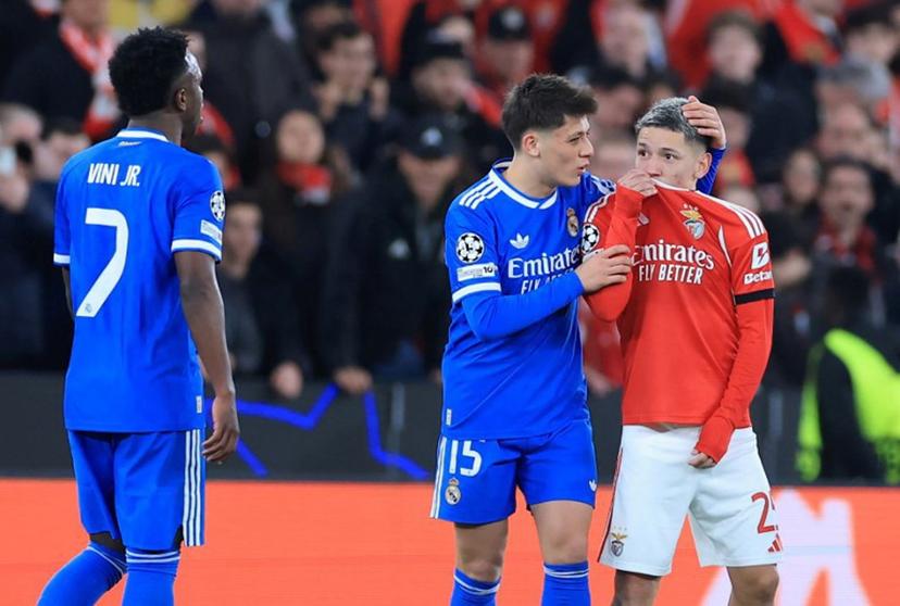 SL Benfica's Argentine forward #25 Gianluca Prestianni hides his mouth while arguing with Real Madrid's Brazilian forward #07 Vinicius Junior who complained about alleged racists insults during the UEFA Champions League knockout round play-off first leg football match between SL Benfica and Real Madrid CF at Estadio da Luz in Lisbon on February 17, 2026.  PATRICIA DE MELO MOREIRA / AFP