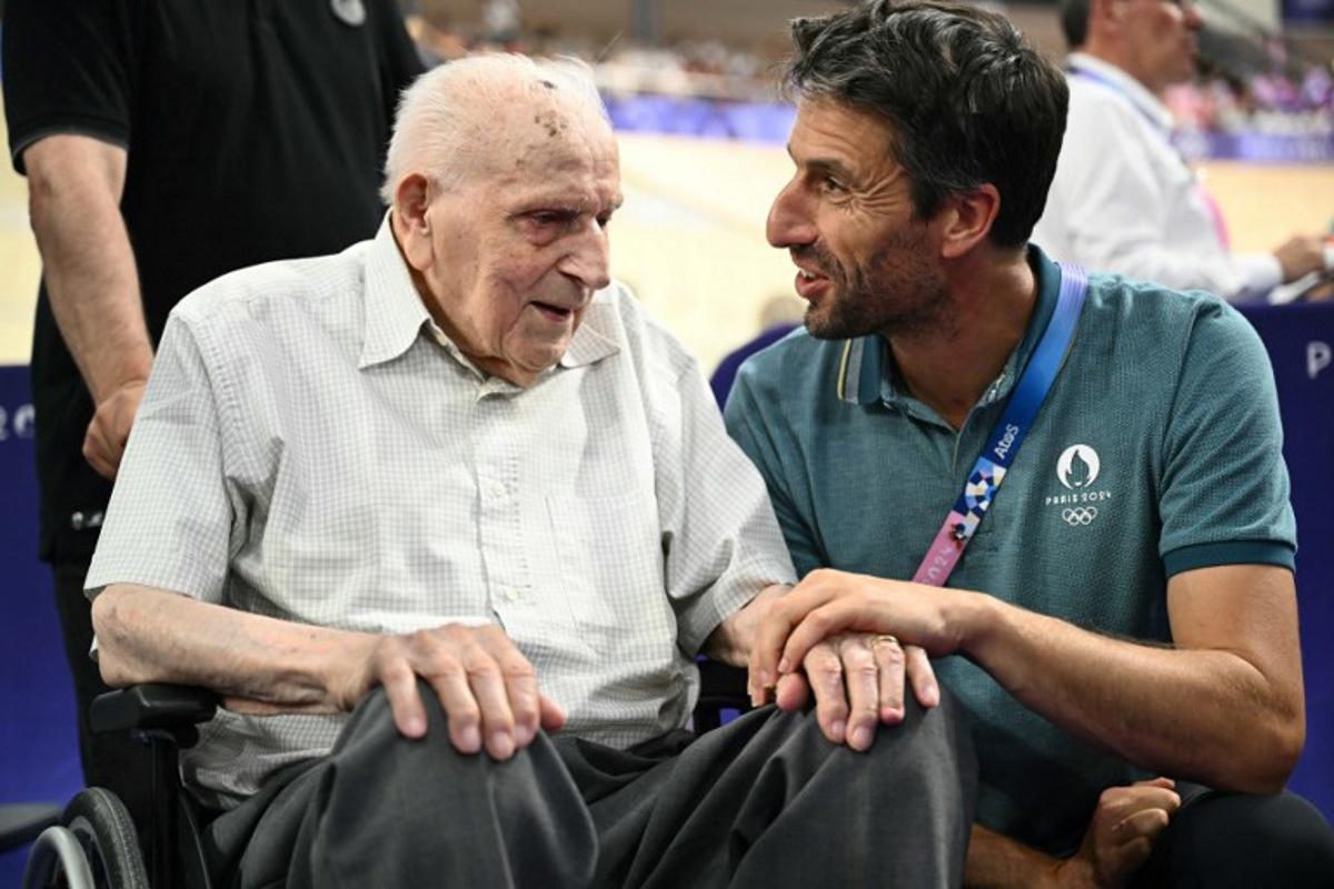 Paris 2024 Olympics and Paralympics Organising Committee (Cojo) chairman Tony Estanguet  (R) speaks with French former cyclist Charles Coste ahead of a sessions of the track cycling event of the Paris 2024 Olympic Games at the Saint-Quentin-en-Yvelines National Velodrome in Montigny-le-Bretonneux, south-west of Paris, on August 7, 2024.  SEBASTIEN BOZON / AFP