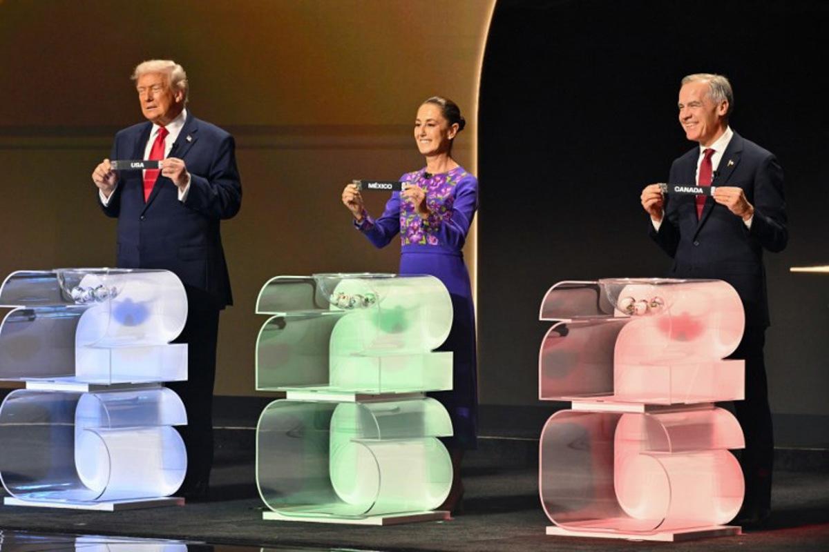 (L/R) US President Donald Trump holds the card reading USA, Mexico's President Claudia Sheinbaum holds the card reading Mexico and Canada's Prime Minister Mark Carney holds the card reading Canada during the draw for the 2026 FIFA Football World Cup taking place in the US, Canada and Mexico, at the Kennedy Center, in Washington, DC, on December 5, 2025. Mandel NGAN / POOL / AFP