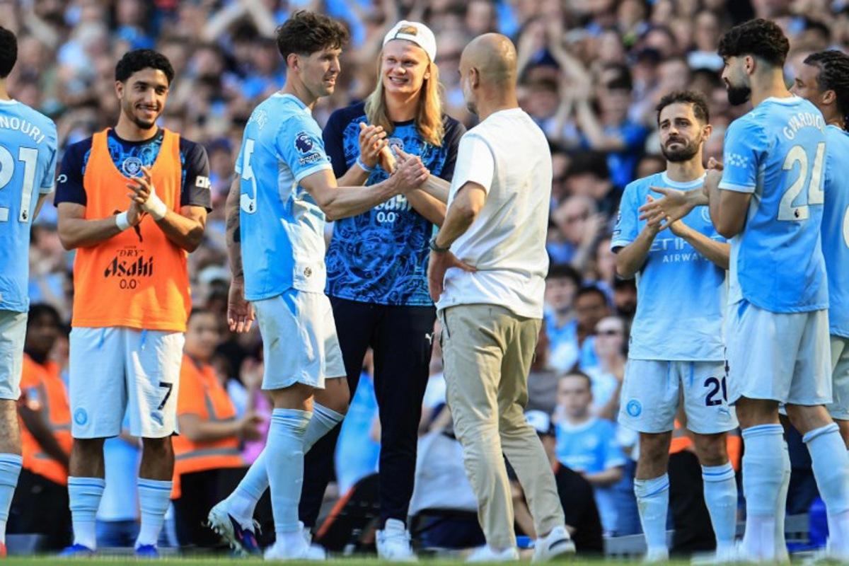 Manchester City's Norwegian striker #09 Erling Haaland (C) looks on as Manchester City's English defender #05 John Stones (2nd L) shakes hands with Manchester City's Spanish manager Pep Guardiola (centre R) after he went through a guard of honour during the English Premier League football match between Manchester City and Aston Villa at the Etihad Stadium in Manchester, north west England, on May 24, 2026. Darren Staples / AFP