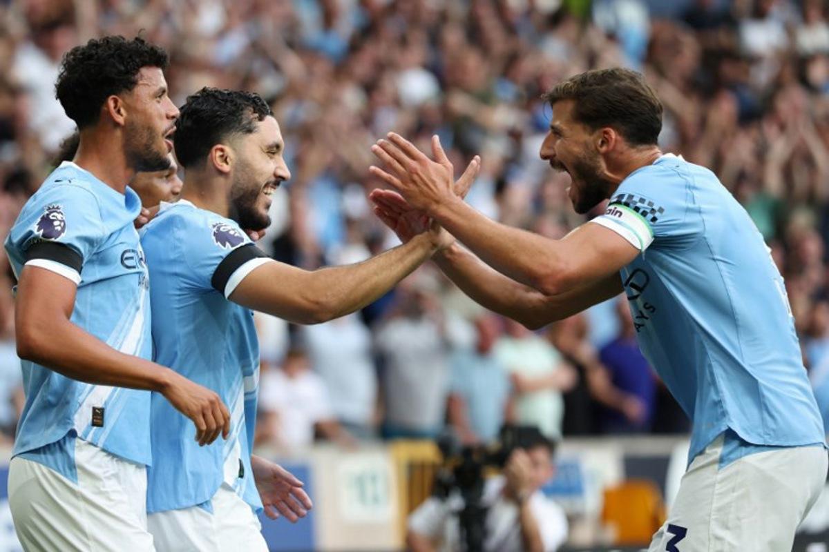 Manchester City's French midfielder #10 Rayan Cherki (2L) celeberates scoring their fourth goal with Manchester City's Portuguese defender #03 Ruben Dias (R) during the English Premier League football match between Wolverhampton Wanderers and Manchester City at the Molineux stadium in Wolverhampton, central England on August 16, 2025. Darren Staples / AFP