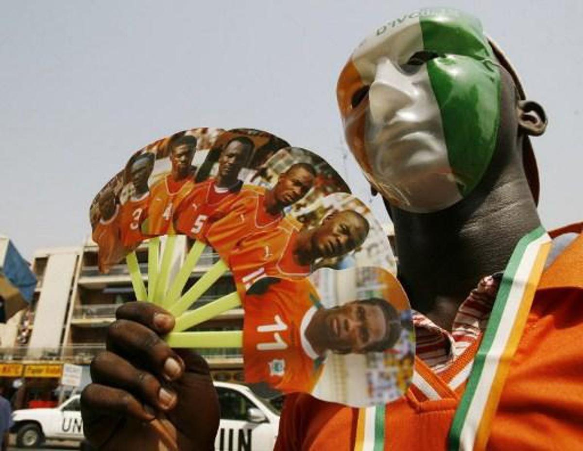 A supporter of the Elephants, the Ivorian national football team, wearing a mask with the Ivorian colours, waves a fan with portraits of the players 24 January 2008 in Abidjan. Ghana's Michael Essien is relishing the prospect of coming up against his Chelsea teammate Didier Drogba's Ivory Coast in the African Nations Cup final. AFP PHOTO / KAMBOU SIA