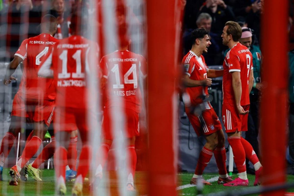 Bayern Munich's English forward #09 Harry Kane celebrates scoring the opening goal with his teammates including Bayern Munich's Croatian defender #44 Josip Stanisic during the German first division Bundesliga football match FC Bayern Munich vs BVB Borussia Dortmund, in Munich, southern Germany on October 18, 2025. Alexandra BEIER / AFP