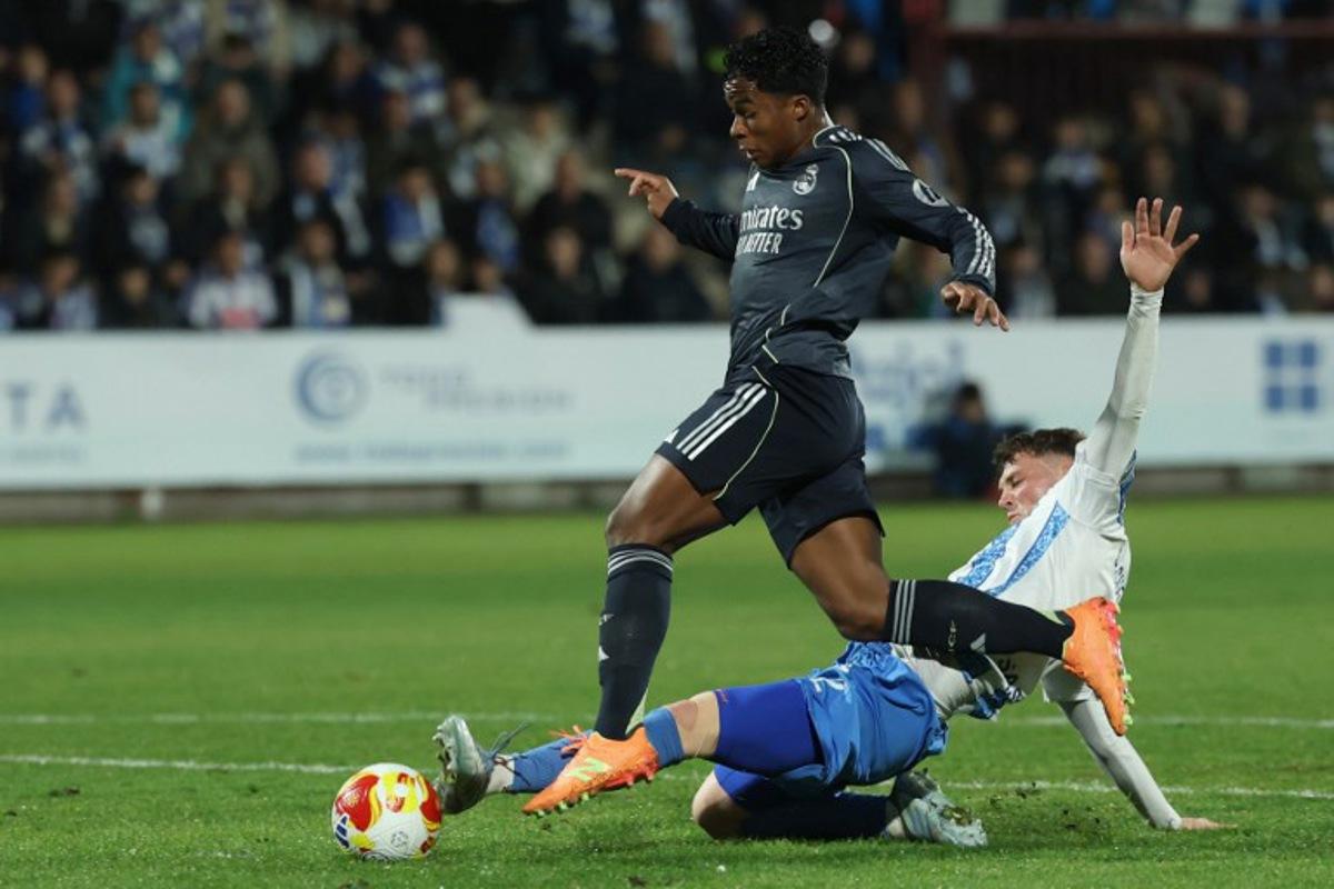 Real Madrid's Brazilian forward #16 Endrick fights for the ball with Talavera's Spanish defender #2 David Cuenca (down) during the Spanish Copa del Rey (King's Cup) round of 32 second leg football match between Talavera CF and Real Madrid CF at El Prado Municipal Stadium in Talavera de la Reina on December 17, 2025. Thomas COEX / AFP