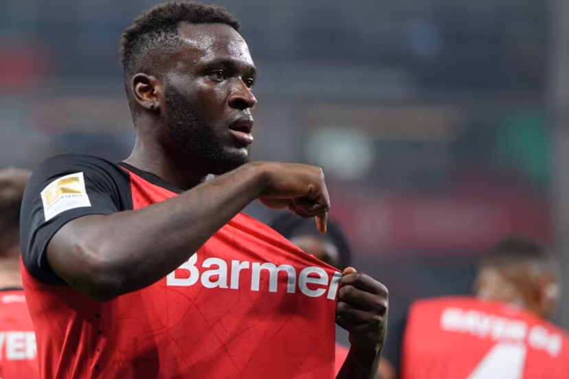 Bayer Leverkusen's Nigerian forward #22 Victor Boniface points to the club badge as he celebrates scoring the 2-1 goal with his teammates during the German first division Bundesliga football match between Bayer 04 Leverkusen and VfL Bochum in Leverkusen, western Germany on March 28, 2025. Pau BARRENA / AFP