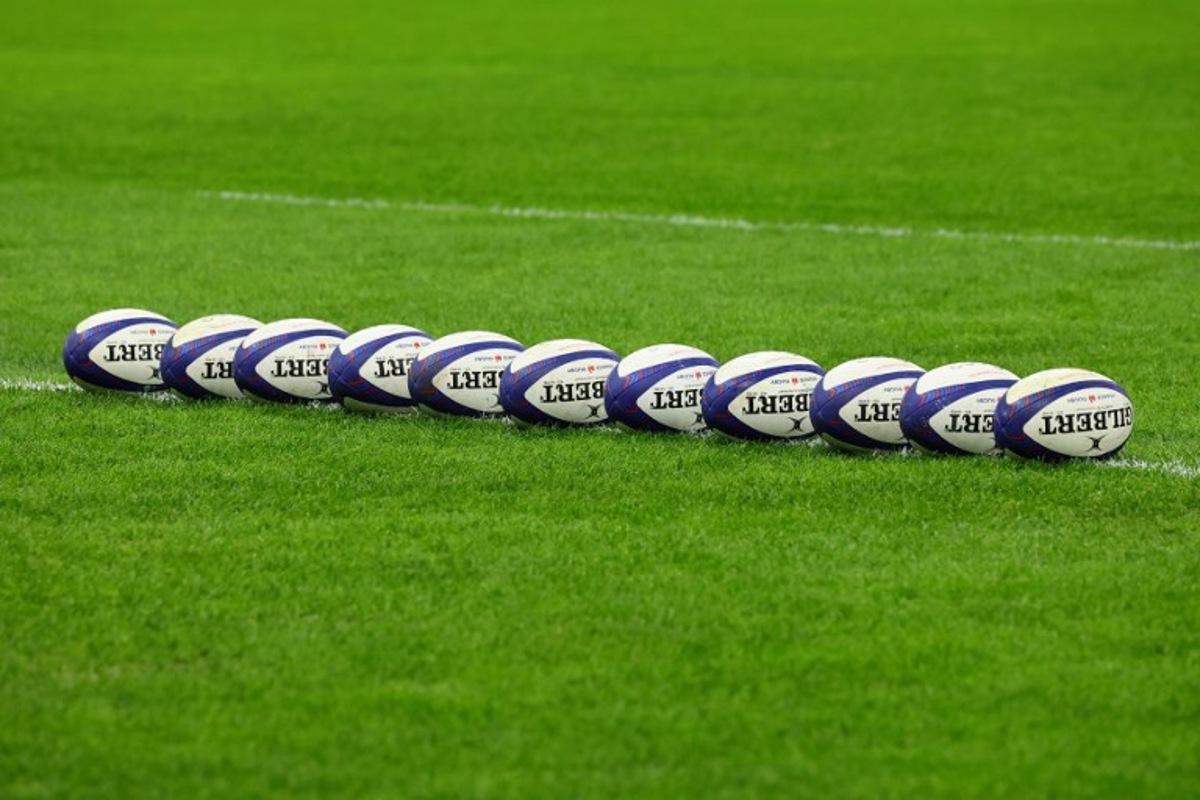 This photograph taken on February 2, 2024 in Marseille, south-eastern France, shows Gilbert match rugby balls lined up on the pitch at the Stade Velodrome ahead of the Six Nations international rugby union match between France and Ireland. CLEMENT MAHOUDEAU / AFP