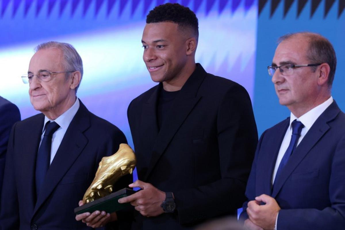 Real Madrid's French forward Kylian Mbappe (C) smiles beside President of Real Madrid Florentino Perez (L), after receiving the 2024-25 European Golden Shoe award honoring the year's leading goalscorer during a ceremony at Santiago Bernabeu Stadium in Madrid on October 31, 2024. Oscar DEL POZO / AFP